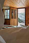 View of snow-capped mountains from a rustic wooden bedroom