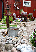 Water feature made from a rusty water pump and old bucket between stones