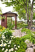 Blumenbeet mit steingesäumten Böschungen, im Hintergrund Gartenpavillon