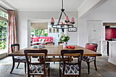 Dining area with wooden table, red accents and garden view