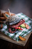 Black burger with fried octopus and vegetables