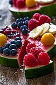 Fruitcake made of watermelon garnished with various fruits sprinkled with coconut flakes
