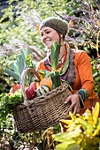 Woman collecting fruit and vegetable while standing in garden