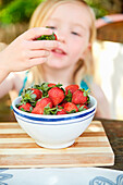 Girl eating stawberries form bowl
