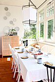 Brightly furnished dining room with white dining table, rattan chest of drawers and Asian pendant light