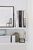 Minimalistisches, weißes Wandregal mit Büchern und dekorativen Objekten