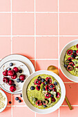 Green matcha tea, banana and date smoothie bowl with cherries, blueberries, kiwi slices and hemp seeds