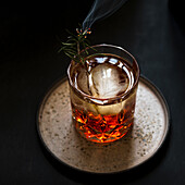 A glass of Negroni with rosemary and ice cubes