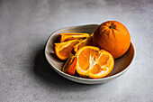 Slices of ripe orange fruits in the stone bowl