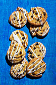 Multiple raisin buns on a blue surface