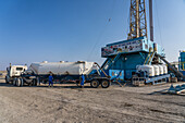 Oilfield workers transferring dry cement from a truck