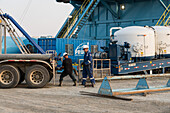 Oilfield workers transferring dry cement into cement tanks