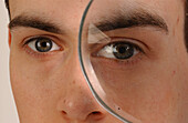 Young man looking through a magnifying glass