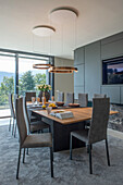 Dining area with wooden table, grey chairs and pendant lights, mountain view