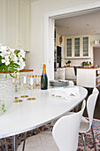 Weißer, ovaler Tisch mit Blumen, Kerzen und Champagner im Essbereich