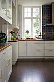 Klassische Einbauküche mit weißen Schrankfronten und Holzarbeitsplatte