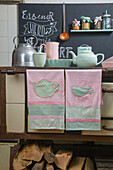 Kitchen towels with teapot and teacup patterns in front of an old wood-burning stove