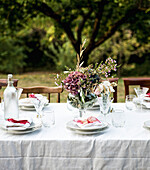 Festlich gedeckter Tisch im Garten mit herbstlichem Blumenstrauß