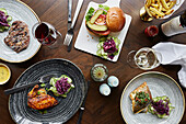 A selection of dishes, steak, chicken, sea bass and a beef burger with fries and wine