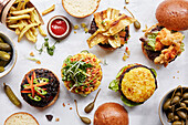An overhead shot of burgers and fries with pickles and caper berries