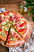 Homemade pizza with zucchini, tomatoes and Parma ham