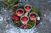 Adventskranz mit Windlichtern, Moos und roten Äpfeln in Vintage Schale im Freien