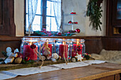 Rote Kerzen in Marmeladengläsern, dekoriert mit Lebkuchen und Kugeln