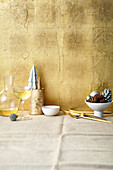 Weihnachtsdeko und Weißwein in Glas und Karaffe vor goldenem Hintergrund