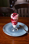A layered dessert with ice cream, raspberries, redcurrants and cream