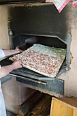 Sliding a bacon with wild garlic topped dough into a wood burning oven