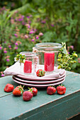Stack of plates, lanterns and fresh strawberries on garden table