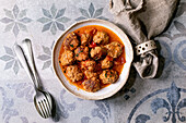 Homemade beef and pork meatballs in tomato sauce in white ceramic plate