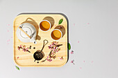 Tea concept, two white cups of tea, teapot, tea strainer and spring sakura branches on concrete background