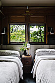 Two single beds and bedside table in old, rustic railway carriage