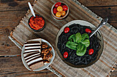Cooked spaghetti with cuttlefish ink arranged with cheese and vegetables