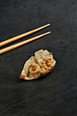 Fried gyoza traditional oriental food placed with bamboo sticks on gray table