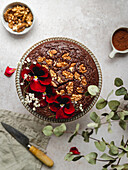 Chocolate cake garnished with red flowers and walnuts served on table