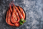Shrimps in bowl with parsley placed on dark marble surface table in luxury restaurant