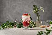Berries and ice cream garnished with nuts and strawberries served on table near glass jars