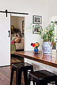 Kitchen counter with wooden top and classic bar stool, view through open sliding door into bedroom