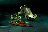 Broccoli, ein ganzer ein halbierter und Röschen auf petrolfarbenem Untergrund