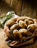 Potatoes in a burlap bag next to rosemary
