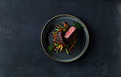 Fillet of beef with julienne cut vegetables on dark stone background
