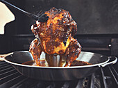 Tandoori chicken on poultry roaster, brush with marinade