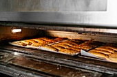 Metal tray with tasty sweet baking placed and preparing in oven in kitchen