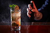 Cocktail mit Gin, Eiswürfeln, Zitrone und Petersilie, mit Infusionssprays besprühen