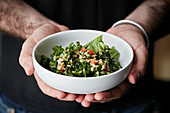Pearl barley and green salad in a bowl held by a waiter