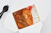 Hähnchen-Katsu-Curry in weißer Box zum Mitnehmen