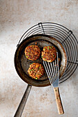 Veal patties with peas and tomatoes in a pan