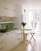 A modern open plan kitchen decorated in neutral colours cupboards sink unit breakfast bar area stools tiled floor